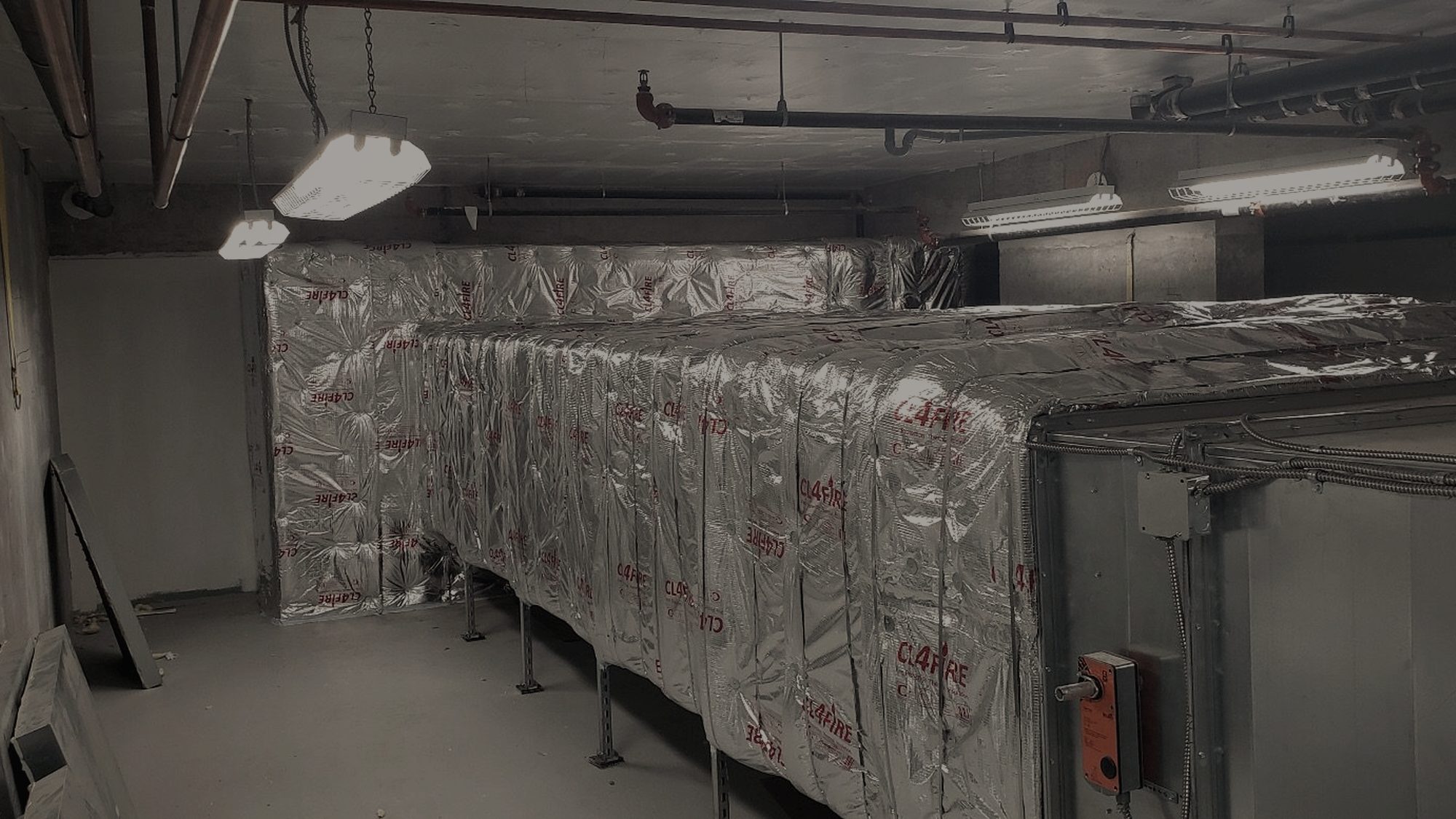 Insulated ductwork running the length of a mechanical room.