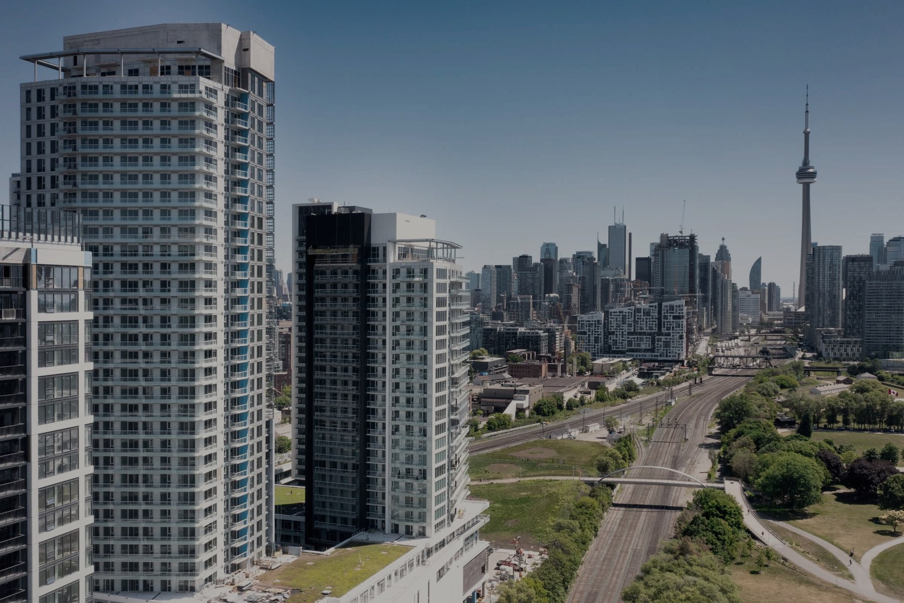 Novus at Garrison Point, Toronto: two residential towers in the foreground with the downtown skyline and the CN Tower behind them.